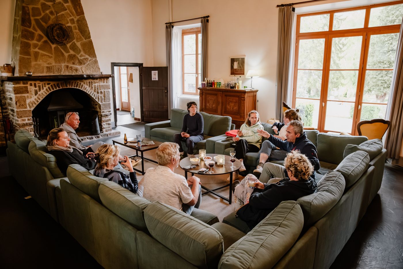 Verschillende mensen drinken een aperitief in de woonkamer van een groot, comfortabel Normandisch huis.